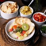 soto betawi jakarta beef milk soup with fried potatoes, tomatoes, emping or melinjo crackers, and thinly sliced green onions